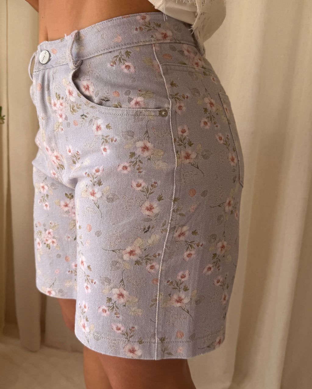 Person wearing a light blue floral skirt with a neutral background